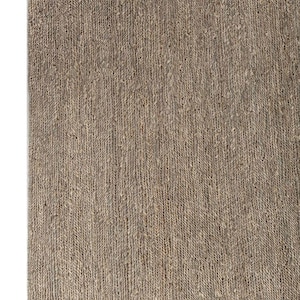 May include: A close-up of a rectangular, woven rug in shades of brown and tan. The rug has a textured surface with vertical lines, creating a natural, rustic appearance. The rug's corner is visible against a white background.