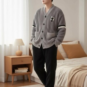 以下が含まれることがあります： 黒と白のストライプのスリーブディテールと黒の「T」パッチが付いたグレーのカーディガンと、黒のテクスチャードパンツ。白いスリッパがコーディネートを完成させています。このアンサンブルは、ラウンジウェアまたはスリープウェアを示唆しています。