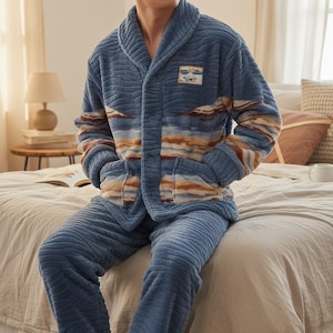 以下が含まれることがあります： 青色の起毛パジャマセット。ジャケットはショールカラー、ボタン留め、パッチディテールが特徴。袖とジャケットは茶色とオレンジ色のストライプ模様。パジャマパンツは無地の青色です。