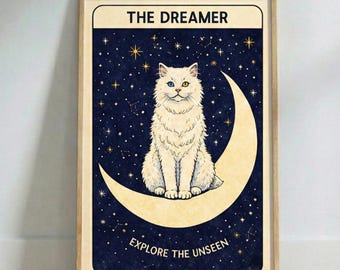 May include: A framed art print depicting a white cat with mismatched eyes, perched on a crescent moon. The background is a dark blue night sky with stars. Text includes "THE DREAMER" and "EXPLORE THE UNSEEN". The frame is a light wood colour.