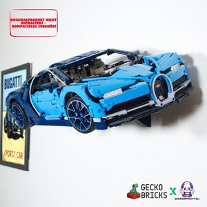 Könnte beinhalten: Ein blaues und dunkelblaues Spielzeug-Sportwagenmodell, das an einer Wand montiert ist. Das Auto verfügt über einen detaillierten Kühlergrill, Scheinwerfer und Räder. Text oben links: ORIGINALPRODUKT NICHT ENTHALTEN! - KOMPATIBLES ZUBEHÖR! GECKO BRICKS Logo.