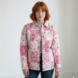 K&ouml;nnte beinhalten: Eine rosa gesteppte Jacke mit einem Patchwork-Design mit floralen Mustern. Die Jacke hat eine Knopfleiste vorne, einen Kragen und lange &Auml;rmel. Der Blumendruck umfasst Rosa- und Wei&szlig;t&ouml;ne.