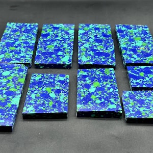 May include: Eight rectangular slabs of azurite and malachite composite material, each featuring a vibrant speckled pattern of deep royal blue, bright turquoise, and lime green mineral inclusions arranged in a grid on a dark surface.