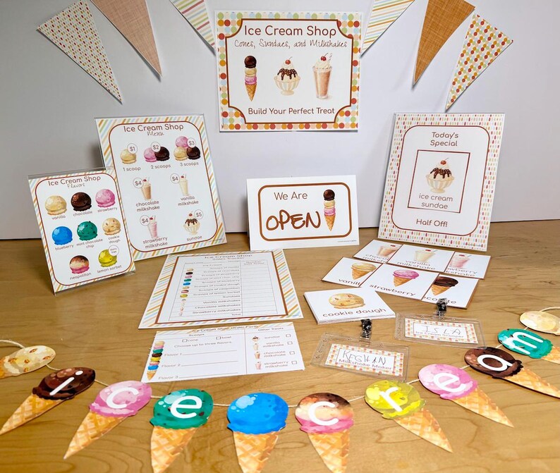 May include: An ice cream shop pretend play set featuring printed signs, menus, and order forms with illustrations of cones, sundaes, and milkshakes. Includes a banner with ice cream cone cutouts spelling out the word ice cream and name tags.