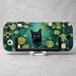 May include: A handheld gaming console featuring a decorative skin with a black cat swimming in a pond filled with green lily pads and white water lilies. The device has black joysticks, directional buttons, and action buttons on the sides.