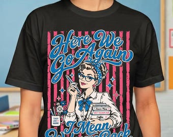 May include: A black t-shirt featuring a graphic of a person with glasses and a blue headband holding a stack of books. The text reads Here We Go Again I Mean Welcome Back. The design includes a mug with flowers and pink vertical stripes.