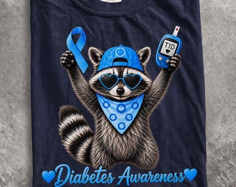 May include: A navy blue t-shirt featuring a graphic of a raccoon wearing a blue baseball cap, heart-shaped sunglasses, and a blue polka-dot bandana. The raccoon holds a blue awareness ribbon and a blood glucose monitor labeled T1D. Text reads Diabetes Awareness.