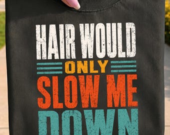 May include: A black crew neck t-shirt featuring distressed, multi-colored text that reads "HAIR WOULD ONLY SLOW ME DOWN". The design uses white for the top line, yellow for the word "ONLY", orange for "SLOW ME", and teal for the word "DOWN".