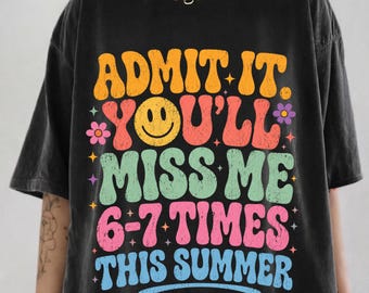 May include: A black short-sleeve t-shirt featuring a multi-colored graphic with the text ADMIT IT. YOU'LL MISS ME 6-7 TIMES THIS SUMMER. The design includes a yellow smiley face, small star icons, and flower shapes in orange, red, green, pink, and blue.