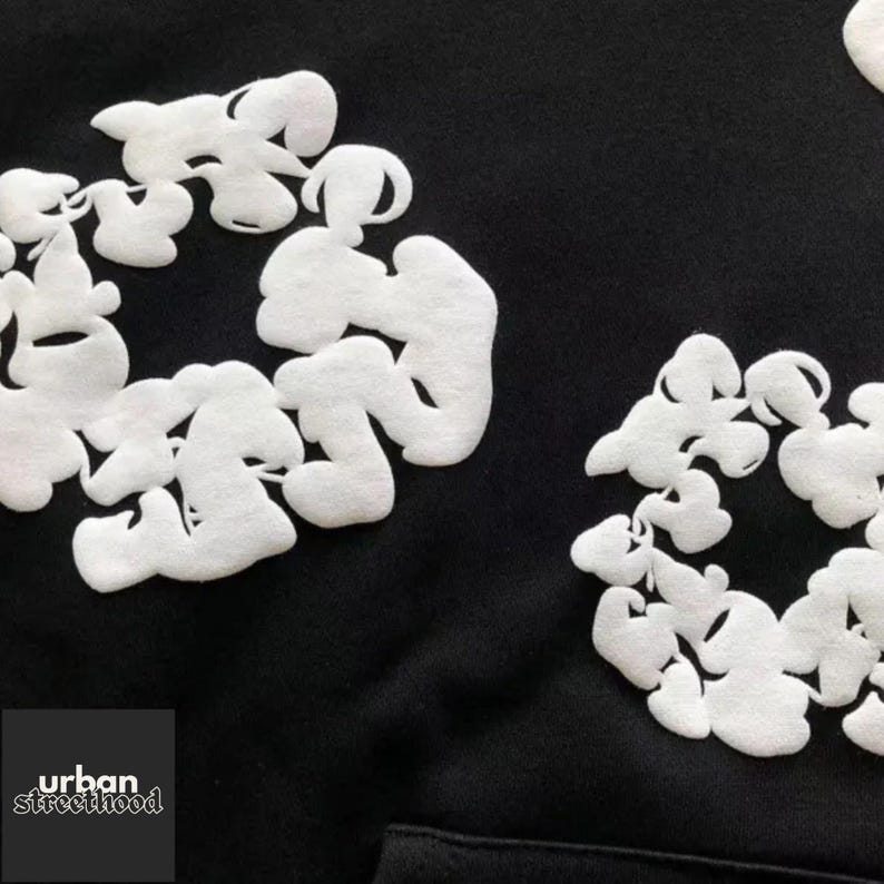 May include: Black hoodie with white, cloud-like, abstract design elements. The design is repeated across the fabric. The lower left corner features the text "urban streetthood" in white.