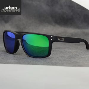May include: Black sunglasses with green and blue mirrored lenses. The sunglasses have a square frame and the text "urban street hood" in the upper left corner.