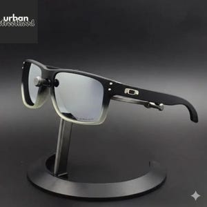 May include: Black and grey sunglasses with a silver mirrored lens. The sunglasses have a rectangular frame with a gradient effect on the lower portion of the lenses. The brand name "urban street hood" is in the upper left corner.