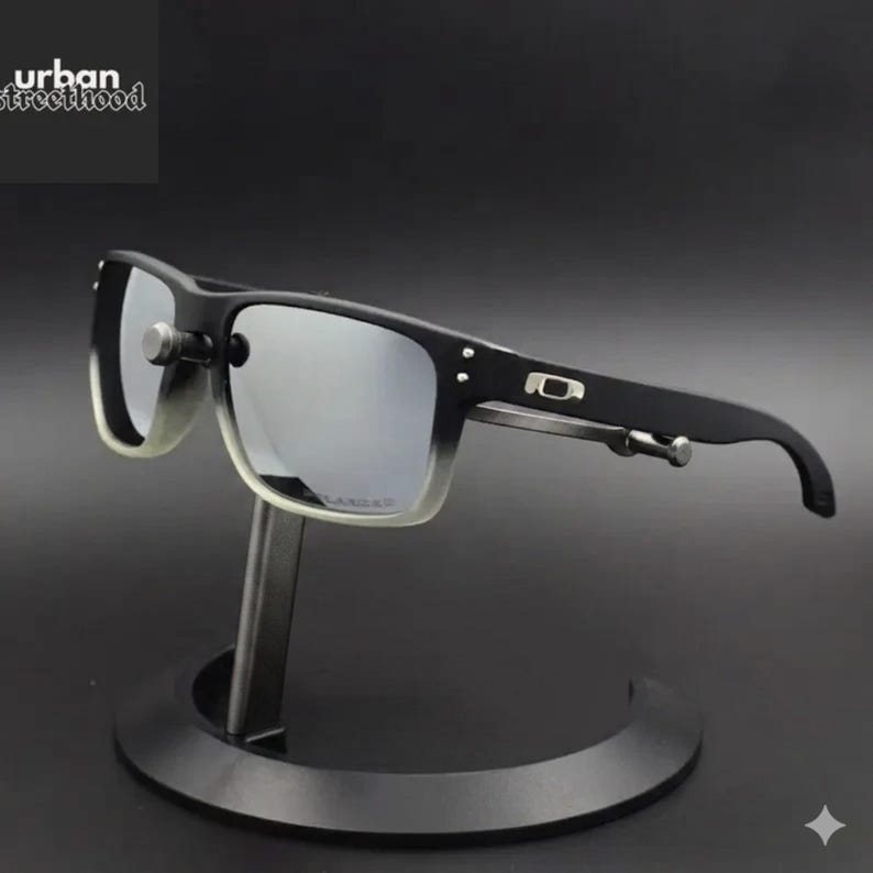 May include: Black and grey sunglasses with a silver mirrored lens. The sunglasses have a rectangular frame with a gradient effect on the lower portion of the lenses. The brand name "urban street hood" is in the upper left corner.