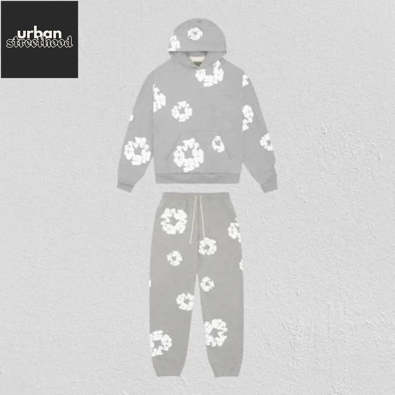 May include: A gray hoodie and matching sweatpants set. The clothing set features a white floral pattern. The hoodie has a drawstring hood and a front pocket. The sweatpants have a drawstring waist. The Urban Street Hood logo is in the top left corner.
