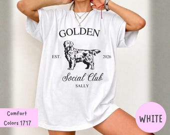 Puede incluir: Una camiseta blanca de manga corta con un gráfico negro de un perro Golden Retriever. El texto dice GOLDEN, EST. 2026, Social Club y SALLY. La camiseta incluye una pequeña etiqueta rosa en la esquina con el texto Comfort Colors 1717.