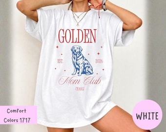 Puede incluir: Una camiseta blanca de manga corta con un gráfico azul de un perro golden retriever. El texto dice GOLDEN, EST. 2026, Mom Club y CHARLI en letras rojas. Pequeños iconos de estrellas rojas están dispersos alrededor de la ilustración central.