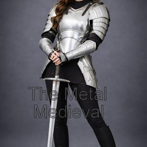 May include: A person wearing polished silver metal armor, including a breastplate, shoulder guards, and arm protection. The person is holding a long silver sword. The text "The Metal Medieval" is visible on the image.