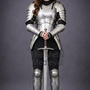 May include: A full suit of polished metal armor, including a breastplate, pauldrons, arm and leg protection, and a helmet. The armor is worn over a black outfit. A long sword is held in front of the body. The text "The Metal Medieval" is visible.