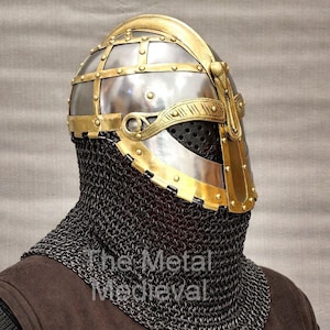 Può includere: Un elmo medievale con finitura in metallo lucido e dettagli in ottone. L'elmo presenta una costruzione rivettata, una protezione per il viso e una protezione per il collo in cotta di maglia. Il testo "The Metal Medieval" è visibile.