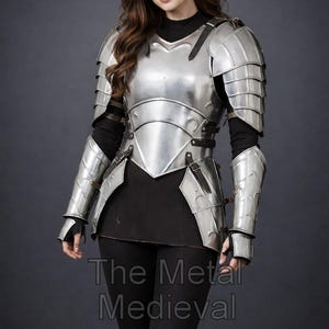 May include: A polished silver medieval armor set, including a breastplate, shoulder guards, and arm protection. The armor is worn over a black top and leggings. The Metal Medieval is printed at the bottom.