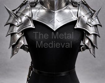 May include: Silver-colored metal shoulder armor with layered pauldrons and a high collar. The armor is displayed on a black dress form. The Metal Medieval is printed on the dress form.