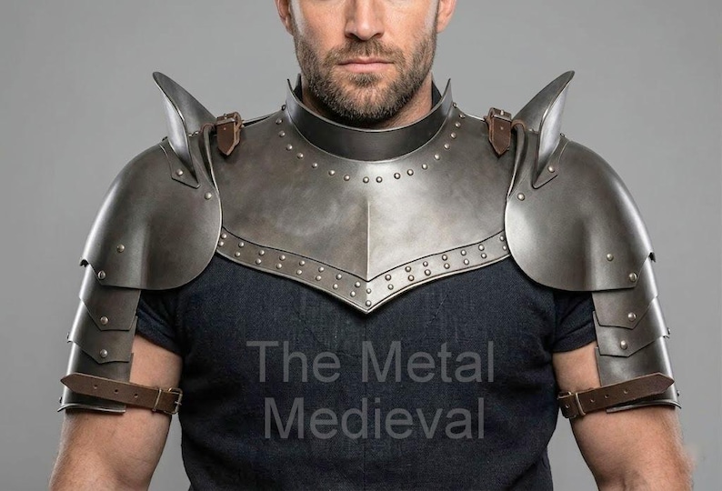 May include: A steel-colored medieval shoulder armor set with a neck guard and shoulder plates. The armor is riveted and has leather straps. The text "The Metal Medieval" is visible on the dark blue shirt.