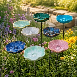 May include: A selection of ceramic flower-shaped garden ornaments in various colours. Each piece, mounted on a metal stake, features a unique hue, such as blue, green, pink, and teal, designed for easy placement in a garden or flower bed.