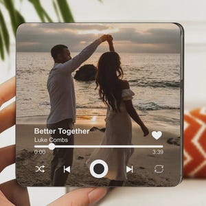 May include: A square, clear acrylic block featuring a photo of a couple dancing on a beach at sunset. The image includes the text "Better Together" and the artist "Luke Combs" with a music player interface.