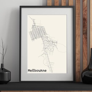 May include: A framed print featuring a detailed, minimalist map of Melbourne, Australia, rendered in black lines on a cream background. The city's name is printed in a simple font at the bottom. The frame is black.