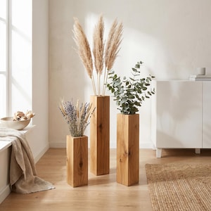 May include: Three rectangular wooden vases of varying heights crafted from light brown timber with visible grain and knots. The vases hold dried pampas grass, lavender, wheat stalks, and green eucalyptus branches, creating a natural arrangement.