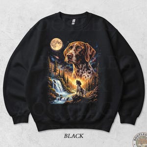 May include: Black sweatshirt with a detailed illustration of a dog set against a backdrop of a waterfall, forest, and full moon. The design includes a smaller dog figure and the word "BLACK".