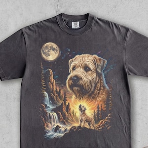May include: A charcoal grey short-sleeve t-shirt featuring a graphic print of a shaggy dog, a smaller dog standing on a rock, a waterfall, rocky cliffs, and a full moon in a night sky. The shirt has a crew neckline and a relaxed fit.