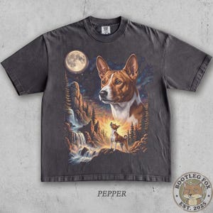 May include: A charcoal gray short-sleeve t-shirt featuring a graphic print of a Basenji dog. The design includes a large portrait of the dog, a smaller dog howling at a bright full moon, a rocky mountain landscape, and a flowing waterfall.