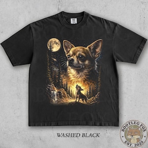 Pu&ograve; includere: T-shirt nero con un'illustrazione dettagliata di un Chihuahua in una scena simile a un lupo. Il design include una luna piena, pini e una cascata. Il testo "Washed Black" &egrave; stampato in basso.