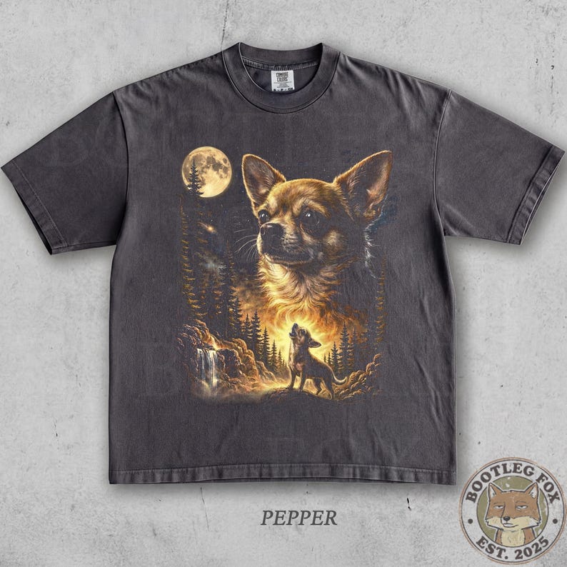 Pu&ograve; includere: T-shirt grigio scuro con un'illustrazione dettagliata di un cane Chihuahua su uno sfondo di foresta e luna. Il design include un cane che ulula e il testo "PEPPER". Un logo di volpe si trova in basso a destra.