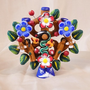 Peut inclure: Une sculpture d'arbre en céramique colorée avec des fleurs, des feuilles et des personnages. L'arbre a un tronc brun avec des fleurs rouges, blanches et bleues, des feuilles vertes et de petites baies rouges.