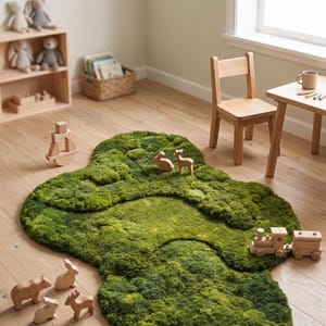 May include: A green, moss-like rug in a child's room, shaped like a stylized landscape. Wooden toy animals and a train are scattered on the rug. A small wooden table and chair are nearby.
