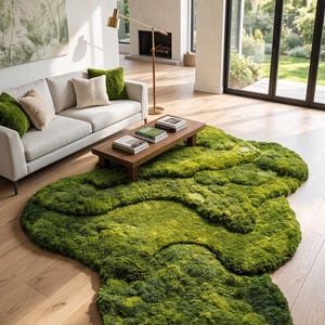 May include: A vibrant green, moss-like rug dominates the foreground of a modern living room. The rug's irregular shape and texture create a natural, organic feel. A light-colored sofa with matching pillows sits against a white wall. A wooden coffee table and a gold lamp complete the scene.