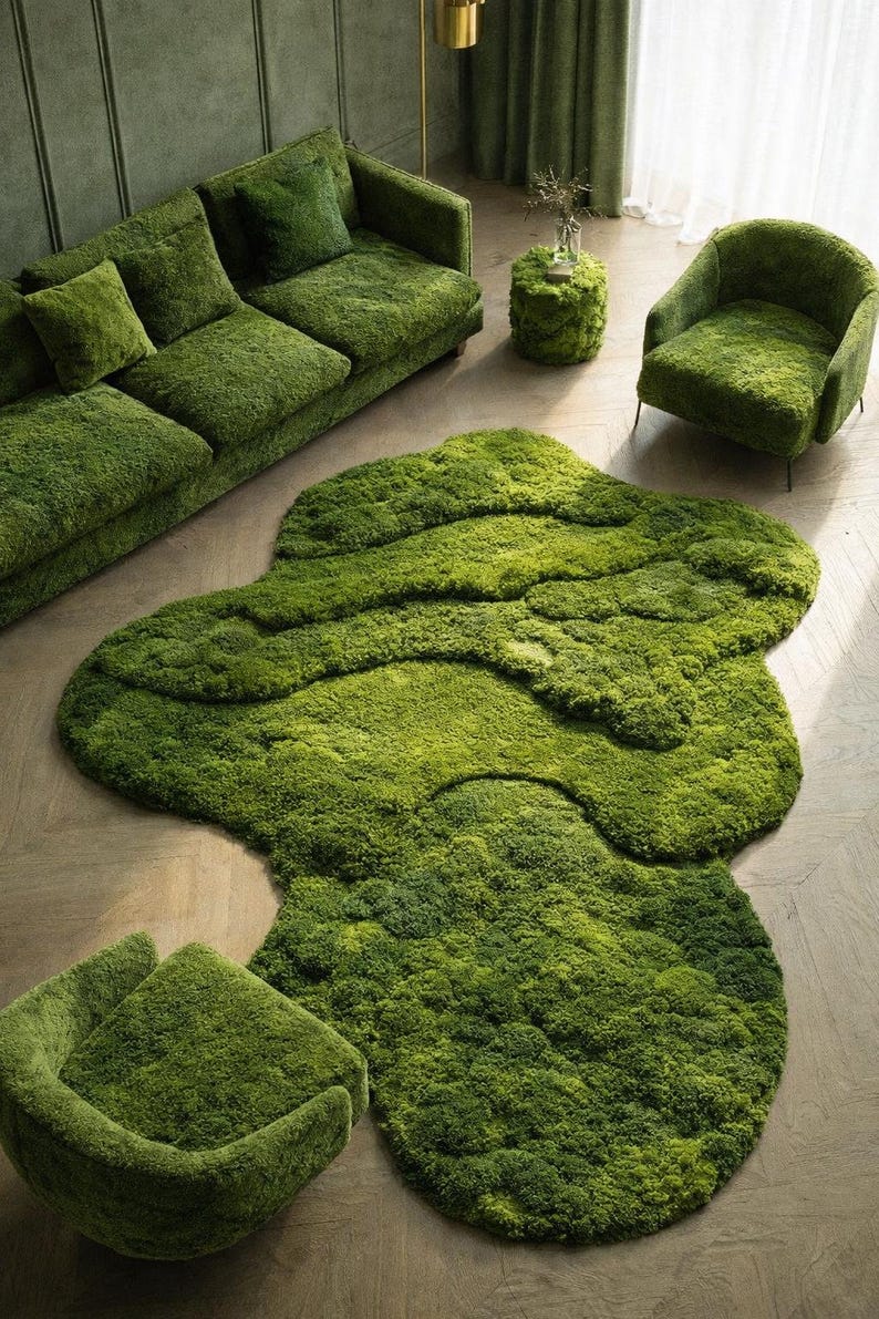 May include: A green moss-covered living room set, including a sofa with pillows, an armchair, a small round table, and a unique rug. The rug has an organic shape. The furniture is a vibrant green color, creating a natural, earthy aesthetic.