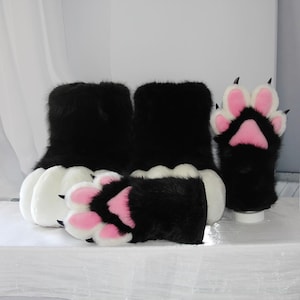 Peut inclure: Gants et bottes en forme de pattes d'animaux, noirs et blancs, avec coussinets roses et griffes noires. Les bottes ont des coussinets blancs. Les gants et les bottes sont conçus pour ressembler à des pattes d'animaux.