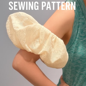 Könnte beinhalten: Cremefarbene Puffärmel aus Spitzenstoff. Der Text "PUFF SLEEVE SEWING PATTERN" ist in weißen Blockbuchstaben dargestellt. Der Ärmel wird an einem Arm gezeigt, mit einem türkisfarbenen Tanktop im Hintergrund.