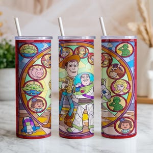 Puede incluir: Tres vasos de acero inoxidable con un colorido dise&ntilde;o de vidrieras con personajes de la pel&iacute;cula Toy Story. Cada vaso tiene una pajita blanca y un borde rojo. El dise&ntilde;o incluye a Woody, Buzz Lightyear y otros personajes.