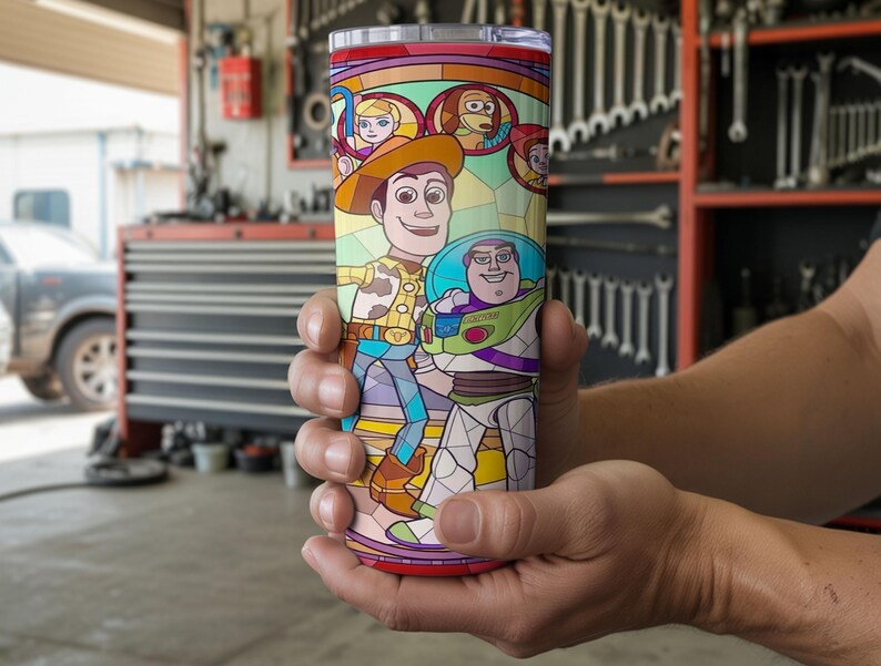 Puede incluir: Un vaso de acero inoxidable con un colorido dise&ntilde;o de vidriera que presenta a los personajes Woody y Buzz Lightyear de la pel&iacute;cula animada Toy Story. El vaso tiene un borde rojo y una tapa transparente. El dise&ntilde;o incluye otros personajes de la pel&iacute;cula.
