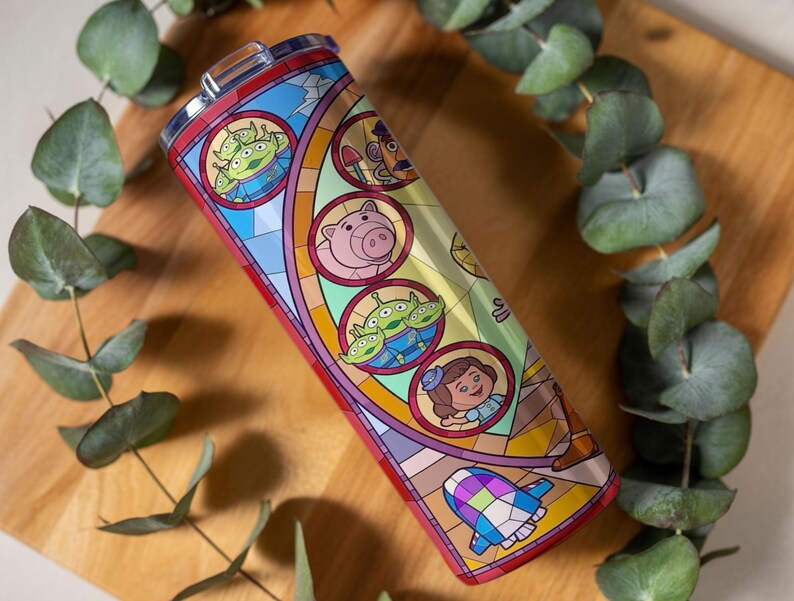Puede incluir: Un vaso de acero inoxidable con un dise&ntilde;o de vidriera que presenta personajes de la pel&iacute;cula animada. El dise&ntilde;o incluye extraterrestres verdes, un cerdo rosa y otros personajes. El vaso mide aproximadamente 20 cm de alto.