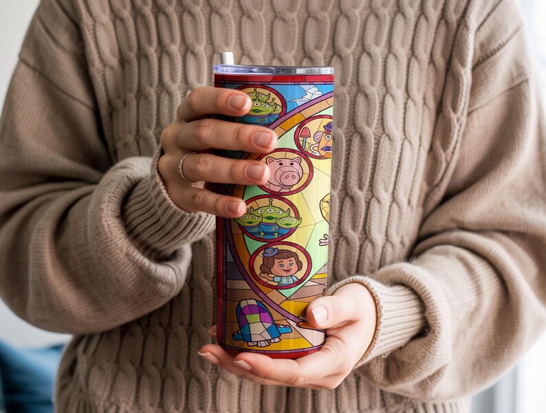 Puede incluir: Un vaso de acero inoxidable con un dise&ntilde;o de vidriera con personajes de dibujos animados. El vaso tiene una tapa transparente y una pajita. El dise&ntilde;o incluye im&aacute;genes de un cerdo, extraterrestres y una ni&ntilde;a.
