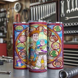 Puede incluir: Tres vasos de acero inoxidable con un dise&ntilde;o de vidriera de colores que presenta personajes de la pel&iacute;cula animada Toy Story. Los vasos son cil&iacute;ndricos y est&aacute;n sobre una superficie met&aacute;lica, con un fondo de taller.