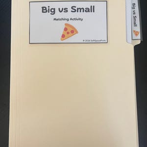 May include: A light beige file folder containing a matching activity. The front label reads Big vs Small Matching Activity with a pizza slice graphic and 2026 SoftSpacePrints text. A matching tab label is visible on the right side.