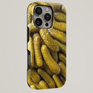May include: A phone case displaying a close-up image of a pile of dill pickles. The pickles are a vibrant yellow-green colour, with a textured surface. The case has a black border and a camera cutout.