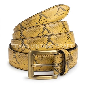 May include: A coiled yellow belt with a snakeskin pattern and a rectangular brass buckle. The belt has a textured surface and the words "TEXAS VINTAGE CRAFT" are printed on the belt.