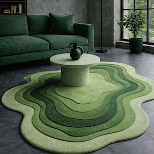 Puede incluir: Una alfombra verde con un diseño único en capas. La alfombra presenta una serie de líneas onduladas concéntricas en diferentes tonos de verde, creando un efecto topográfico. La alfombra está en un salón con un sofá verde y una mesa de centro redonda. Medidas: aproximadamente 200cm x 300cm.